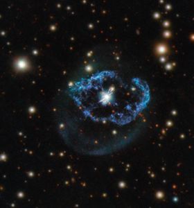 A glowing white center surrounded by a blue-purple shell/ring. Many bright stars glow in the background.